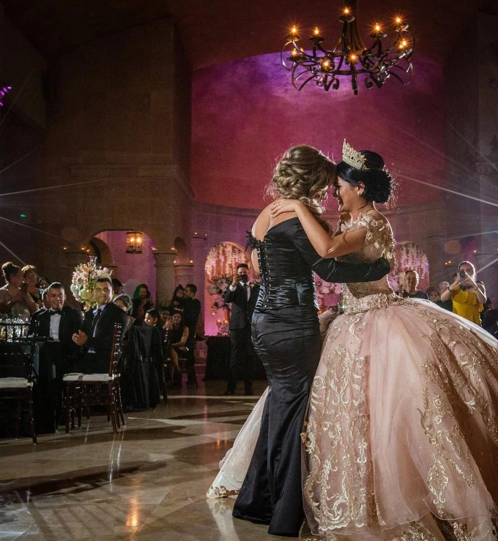 Quinceañera sharing a parent dance under the chandelier in the ballroom at The Bell Tower on 34th, Houston, TX.